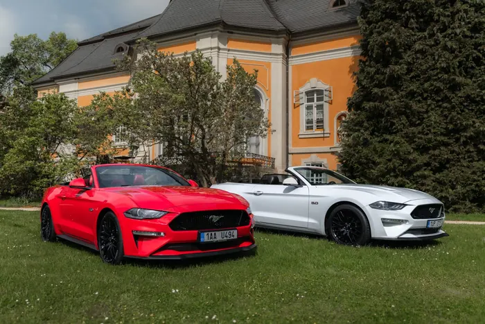 Červený a bílý Ford Mustang GT Cabrio stojící vedle sebe