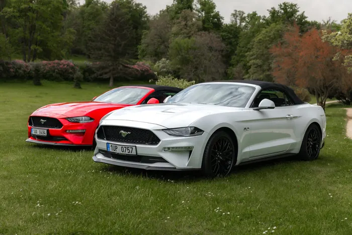Bílý a červený Ford Mustang GT Cabrio v zámeckém parku
