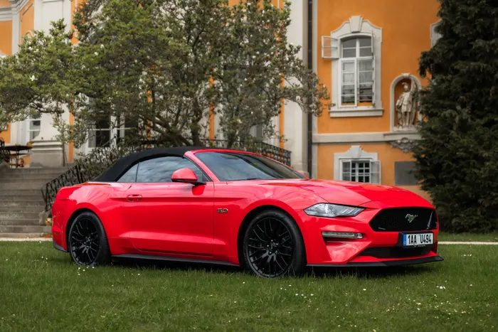 Červený Ford Mustang GT Cabrio se staženou střechou z boku