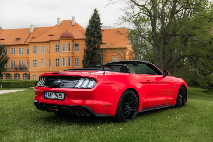 Červený Ford Mustang GT Cabrio zezadu v zámeckém parku