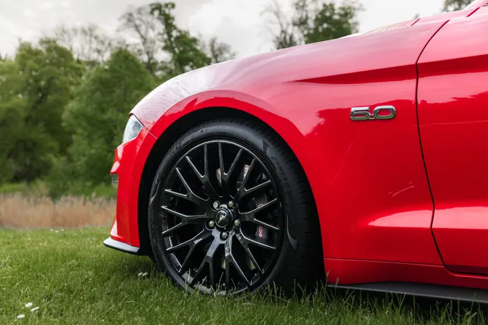 Detail boku a kola červeného Fordu Mustang GT 5.0