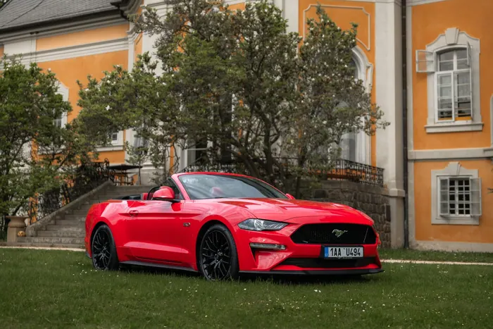 Červený Ford Mustang GT Cabrio z bočního pohledu u zámku