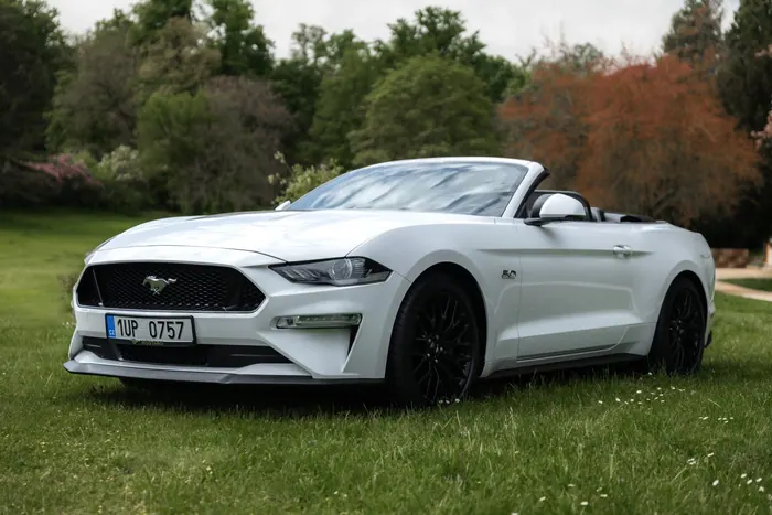 Bílý Ford Mustang GT Cabrio se staženou střechou z boku